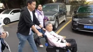 私董善愛圓夢行動義工陪伴長者坐輪椅於東莞街道前行，完成回鄉尋根旅程的一段路