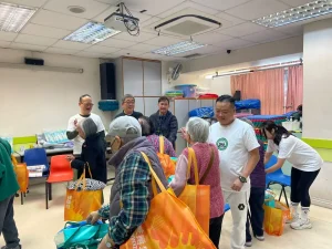 私董善愛暖冬社區關懷行動中，主席黃君俠與義工協助長者有序領取物資，確保現場流程順暢並兼顧每位長者需要